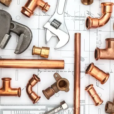 A bunch of copper pipes and tools on top of some plans