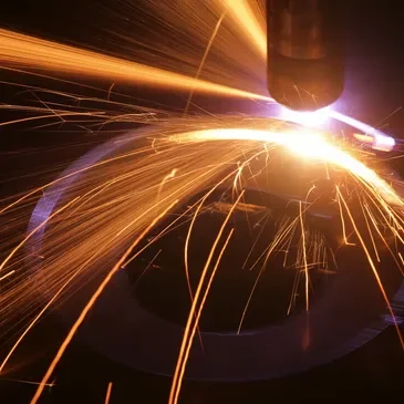 A close up of a metal cutting machine with sparks flying