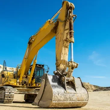 A yellow and black excavator on dirt ground