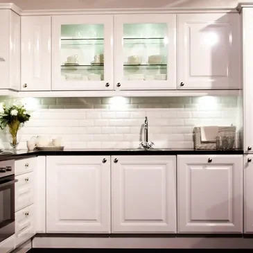 A kitchen with white cabinets and black counter tops.