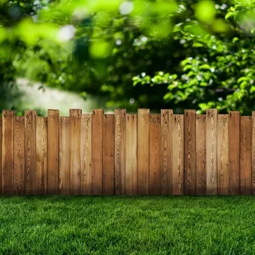 A wooden fence in the middle of a green field.